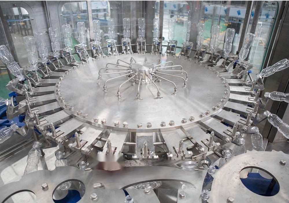 Stainless steel rotary bottle rinsing carousel running in workshop